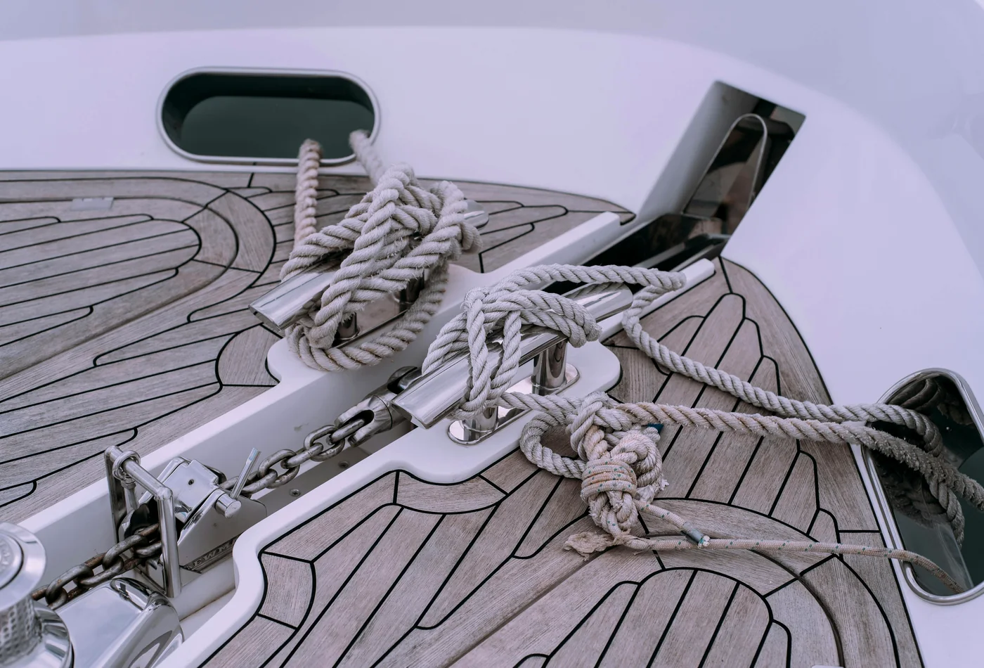 Foredeck with routed deck-panel lines, stainless cleats, rope, and hatch cutouts.