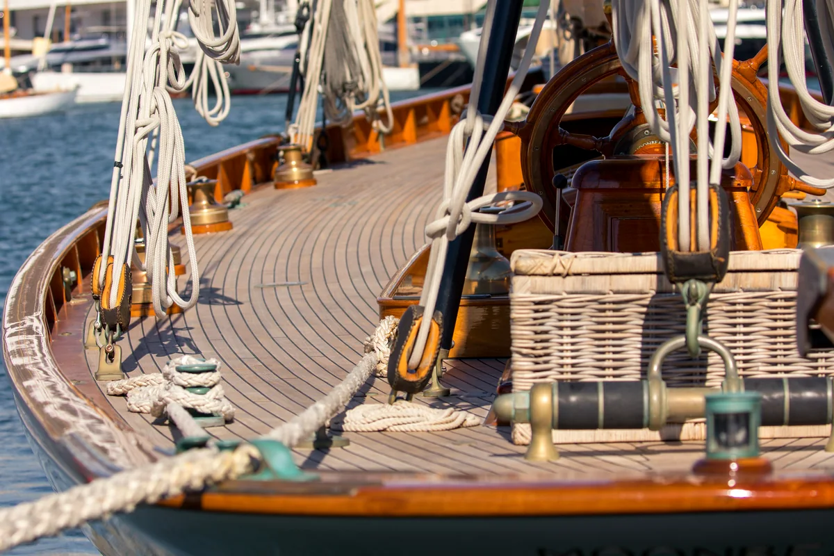 Wood deck with helm wheel, rigging, and long deck seams.