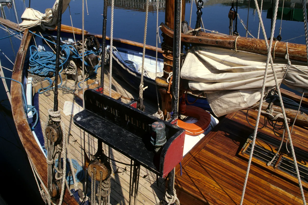 Vintage boat deck with wood planks, rigging, rope, and hatch detail.