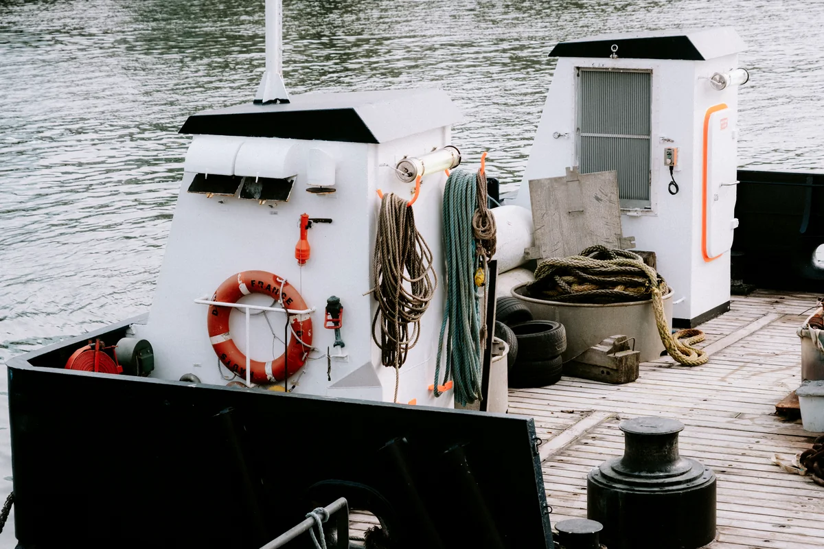 Workboat deck with rope, water, and weathered deck boards.